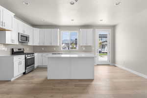 Kitchen with white cabinetry, a wealth of natural light, light hardwood / wood-style flooring, and stainless steel appliances