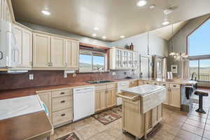 Kitchen featuring sink, white appliances, a wealth of natural light, and light tile patterned floors