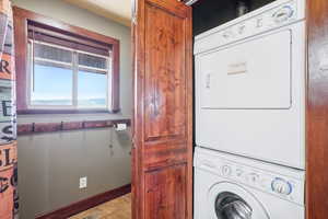 Clothes washing area featuring light tile patterned flooring and stacked washer / drying machine