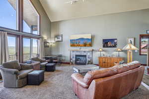 Carpeted living room featuring a tile fireplace and high vaulted ceiling