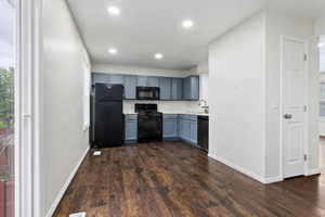 Kitchen with blue cabinets, black appliances, sink, and dark wood-type flooring