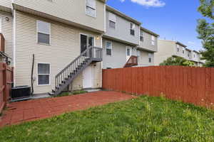 Rear view of house with a patio area, a yard, and central air condition unit