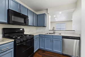 Kitchen featuring black appliances, sink, blue cabinetry, and dark hardwood / wood-style floors