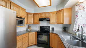 Kitchen with light tile patterned floors, refrigerator, tasteful backsplash, sink, and electric stove