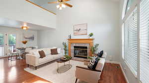 Living room with a towering ceiling, a fireplace, skylights, and ceiling fan