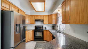 Kitchen featuring light tile patterned flooring, dark granite countertops, and decorative backsplash