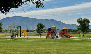 View of jungle gym featuring a mountain view and a lawn