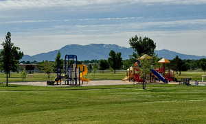 View of jungle gym with a mountain view and a yard