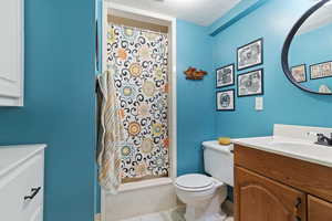 Bathroom featuring a textured ceiling, tile patterned flooring, vanity, and toilet