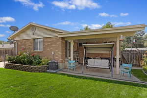 Rear view of house with central AC, a patio area, and a lawn