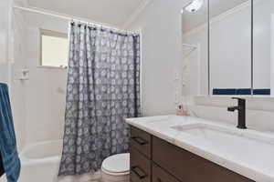 Full bathroom featuring vanity, shower / bathtub combination with curtain, toilet, and crown molding