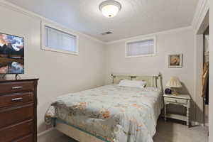 Carpeted bedroom with a textured ceiling and ornamental molding