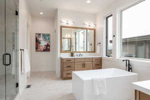 Bathroom with a healthy amount of sunlight, vanity, and plus walk in shower