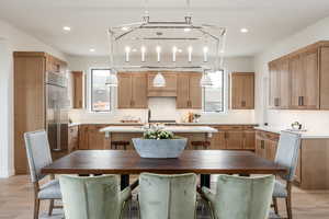 Interior space featuring stainless steel built in fridge, light hardwood / wood-style flooring, hanging light fixtures, and tasteful backsplash