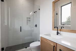 Bathroom with a shower with door, vanity, and toilet