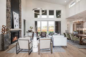 Living room with high vaulted ceiling, an inviting chandelier, light hardwood / wood-style flooring, and a fireplace