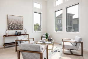 Sitting room with light colored carpet and a towering ceiling