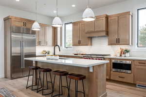 Kitchen featuring light hardwood / wood-style flooring, an island with sink, appliances with stainless steel finishes, and a wealth of natural light