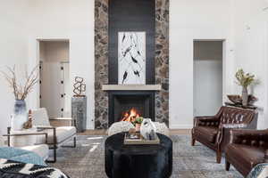 Living room with wood-type flooring, a fireplace, and a towering ceiling