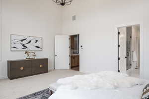 Bedroom with light carpet, a high ceiling, and ensuite bathroom