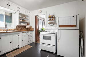 Kitchen with dark hardwood flooring, white appliances, white cabinets, sink, and tasteful backsplash