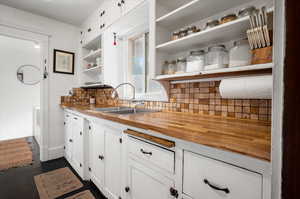 Kitchen featuring sink, white cabinets, backsplash, dark hardwood / wood-style flooring, and butcher block counters