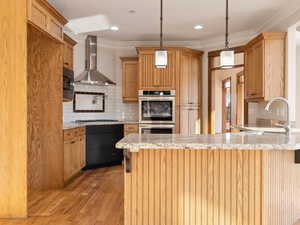 Kitchen with  hardwood  floors, exhaust hood, decorative light fixtures, backsplash, and stainless steel appliances, doubl wall ovens