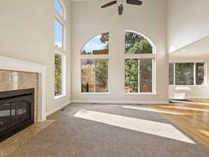 Great room featuring new carpet and hardwood floors, a towering ceiling,  fireplace, and ceiling fans