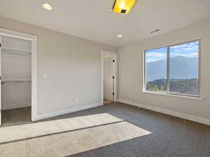 Second bedroom featuring carpet flooring, a mountain view, and a walk-in closet and en-suite bathroom