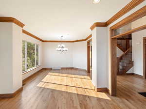 Interior space featuring hardwood flooring, ornamental molding, and an inviting chandelier