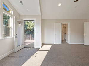 Primary bedroom with lofted ceiling and carpet floors, private deck access