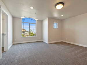 Third bedroom with a textured ceiling and carpeted flooring, picture window