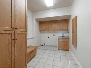 Laundry area with electric dryer hookup, sink, light tile floors, and washer hookup, built in ironing board