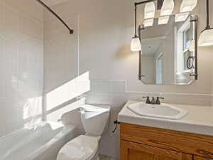 Full bathroom featuring toilet, tile walls, backsplash, tiled shower / bath combo, and vanity