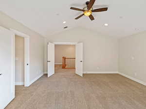 Bedroom with ceiling fan, light carpet, and vaulted ceiling