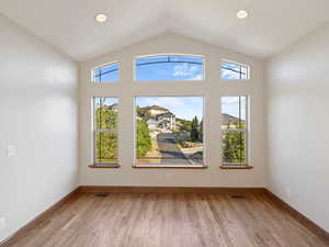 Living room featuring lofted ceiling, hardwood floors and wall of windows