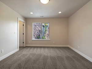 Fourth bedroom with a textured ceiling and carpet and shared bathroom