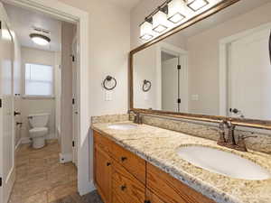 Shared Bathroom featuring tilefloors, dual vanity, and toilet