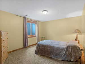 Carpeted bedroom with a textured ceiling and baseboards