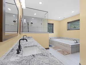 Bathroom featuring double vanity, a walk in shower, a garden tub, and recessed lighting