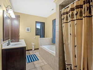 Full bathroom with double vanity, curtained shower, a bath, and light tile patterned floors