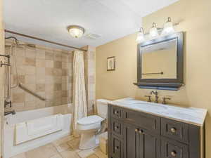 Full bathroom featuring vanity, shower / bathtub combination with curtain, and a textured ceiling