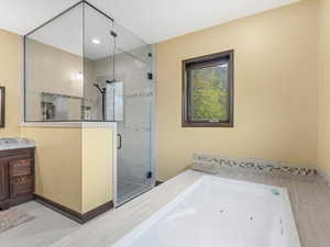 Bathroom featuring vanity, a shower stall, and a jetted tub