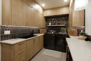 Clothes washing area featuring independent washer and dryer, light tile patterned floors, and sink