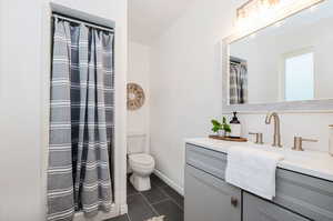 Bathroom with toilet, tile patterned floors, and vanity