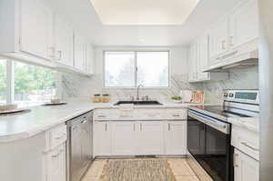 Kitchen featuring light tile patterned flooring, appliances with stainless steel finishes, sink, and white cabinetry