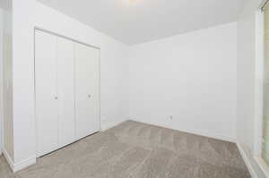 Unfurnished bedroom with light carpet and a closet