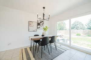 Dining space featuring light tile patterned floors and a chandelier