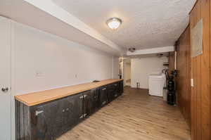 Bar with washer / dryer, a textured ceiling, and light hardwood / wood-style floors