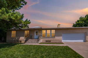 View of front of property featuring a yard and a garage